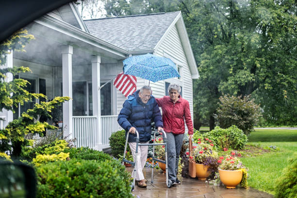 雨の中歩行器で歩行する高齢者